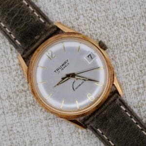 The Truway 17 Jewels Date Incabloc is a vintage wristwatch featuring a gold case, brown strap, white dial with date and time display, 17 jewels movement, and Incabloc shock protection.