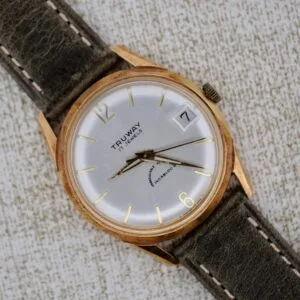 The Truway 17 Jewels Date Incabloc is a vintage wristwatch featuring a gold case, brown strap, white dial with date and time display, 17 jewels movement, and Incabloc shock protection.