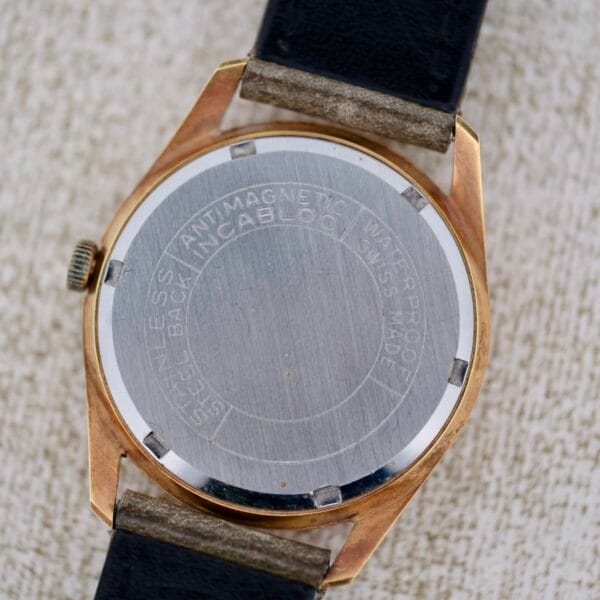 A close-up of the Truway 17 Jewels Date Incabloc wristwatch’s back, showing its round metallic case, black leather strap, and engraved details highlighting antimagnetic, waterproof features and Swiss made quality.