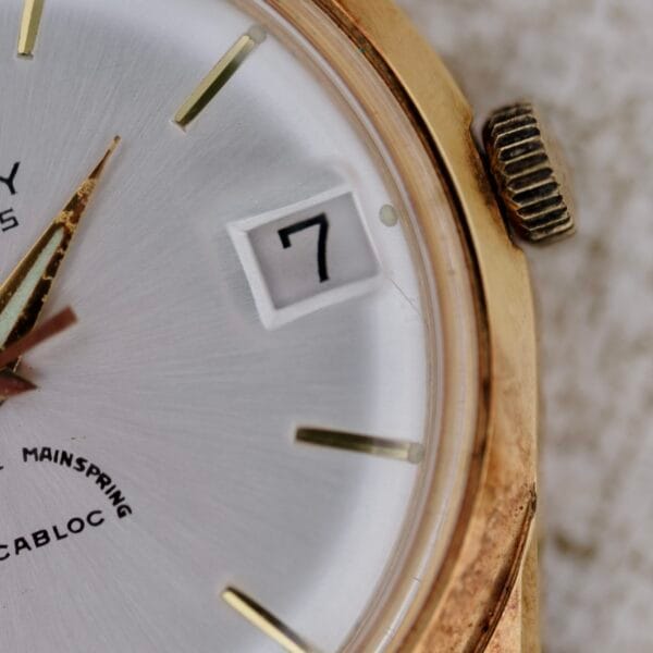 Close-up of a gold Truway 17 Jewels Date Incabloc watch showing part of the face, hands, crown, and date window displaying 7, with the brand name and Incabloc partially visible on the dial.