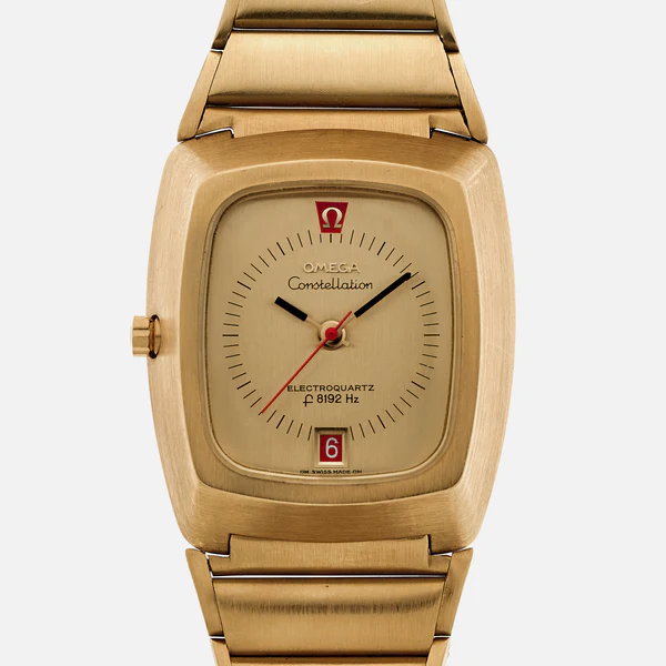 A gold Omega Constellation Electroquartz 196.005 wristwatch with a square case, gold dial, single red seconds hand, and date display at 6 o’clock. The face shows “ELECTROQUARTZ f 8192 Hz” above the date window.