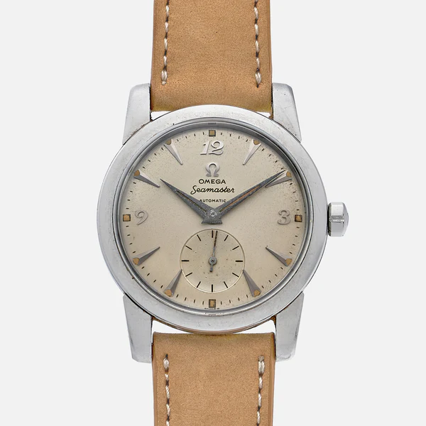 A vintage Omega Seamaster 2576 automatic wristwatch with a beige dial, silver hour markers, small seconds subdial at 6 o’clock, silver case, and a tan leather strap with white stitching.