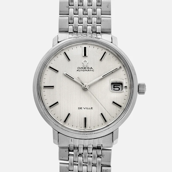 A stainless steel Omega De Ville automatic wristwatch with a silver dial, black hour markers, and a date window at 3 oclock, shown on a metal link bracelet against a white background.