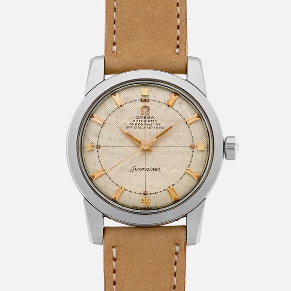 A vintage Omega Seamaster 2767 watch with a beige textured dial, gold hour markers and hands, silver case, and tan leather strap, displayed against a plain white background.