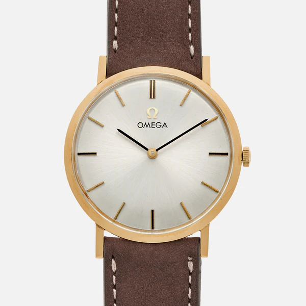 A gold Omega D6672 wristwatch with a white dial, gold hour markers, and black hands, attached to a brown leather strap with white stitching. The watch face displays the Omega logo near the 12 o’clock position.