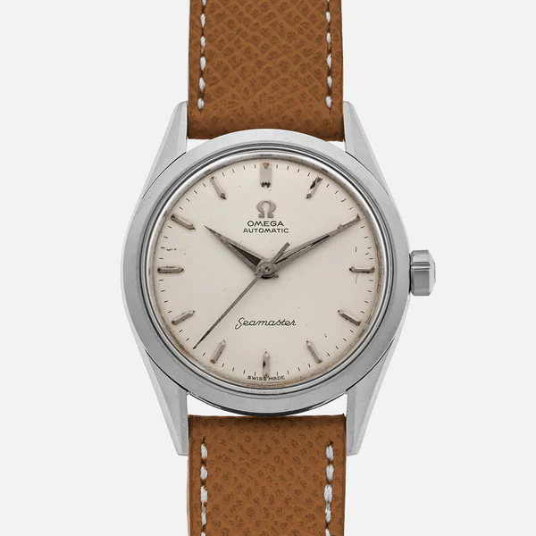 A vintage Omega Seamaster automatic wristwatch with a round silver case, cream dial, simple hour markers, and a brown leather strap with white stitching, displayed against a plain background.