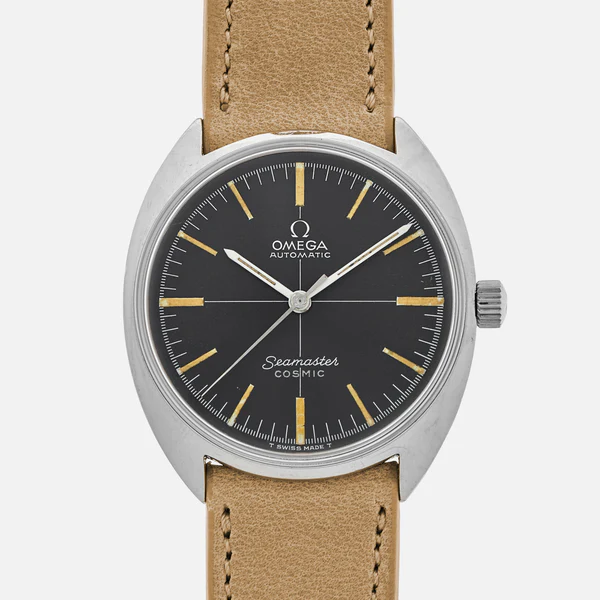 A vintage Omega Seamaster Cosmic wristwatch with a black dial, silver indices and hands, a stainless steel case, and a tan leather strap. The words Omega Automatic and Seamaster Cosmic are visible on the dial.