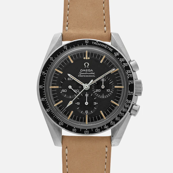 A close-up of an Omega Speedmaster Professional wristwatch with a black dial, chronograph subdials, silver case, and tan leather strap, photographed against a plain white background.