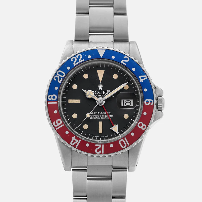 A stainless steel Rolex GMT-Master 1675 wristwatch with a black dial, red and blue bezel, silver hour markers, and a date display set to the 18th, shown on a metal bracelet against a white background.