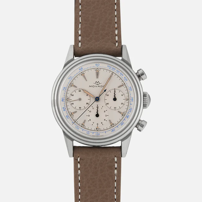A silver Movado 19038 chronograph wristwatch with a beige dial, three subdials, blue and black markings, and a brown textured leather strap, shown against a plain white background.