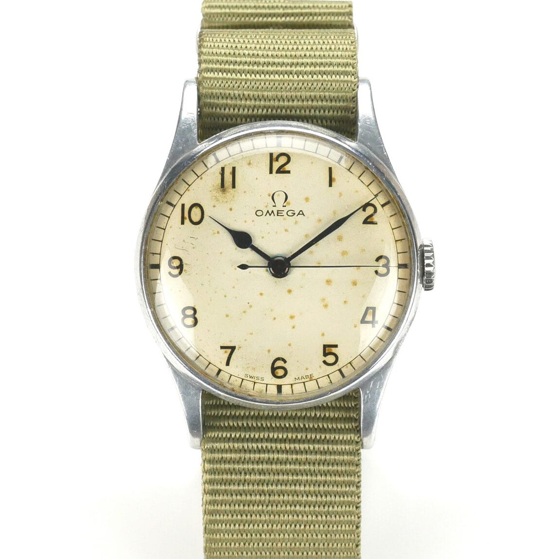 A vintage Omega 6B/159 1943 Issue wristwatch featuring a round, off-white dial with patina, bold black numerals, and two hands in a silver case, paired with a textured khaki fabric strap. The Omega logo sits below the 12 o’clock position.