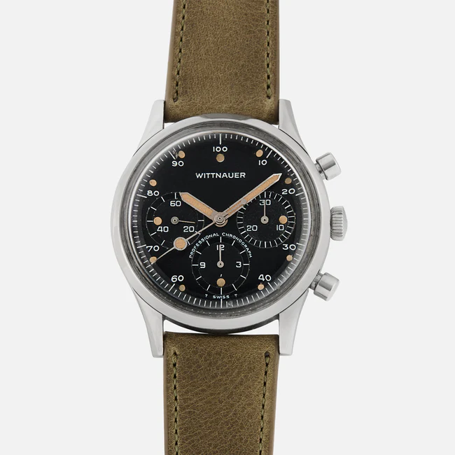 A Wittnauer Chronograph 242T wristwatch featuring a black dial with three subdials, silver case, and brown leather strap. The watch displays a chronograph function with silver hands and indices.