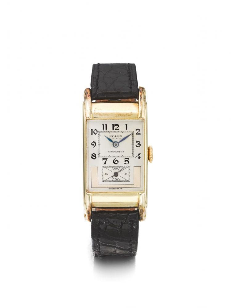 A rectangular gold Rolex Prince wristwatch with a white face, black numbers, and a black leather strap.