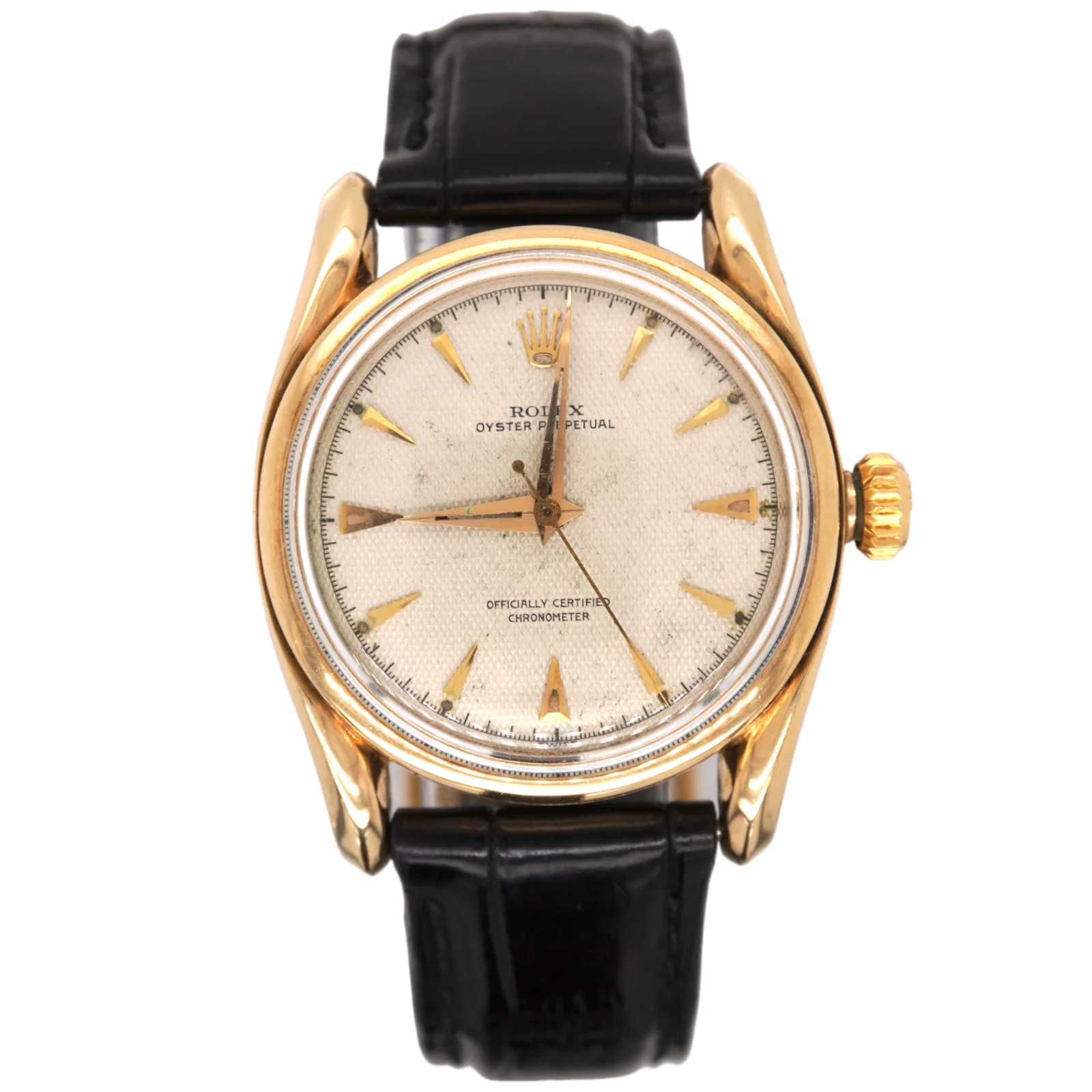 A vintage Rolex Oyster Perpetual gold wristwatch with a black leather strap and a textured white dial.
