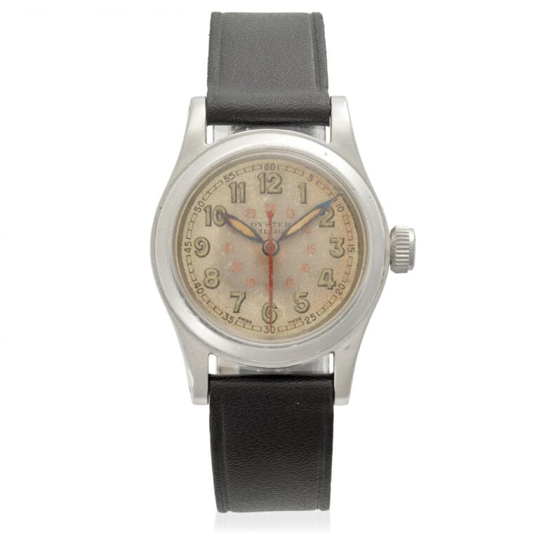 A vintage Rolex wristwatch with a worn beige dial, black leather strap, silver case, and classic Oyster design.