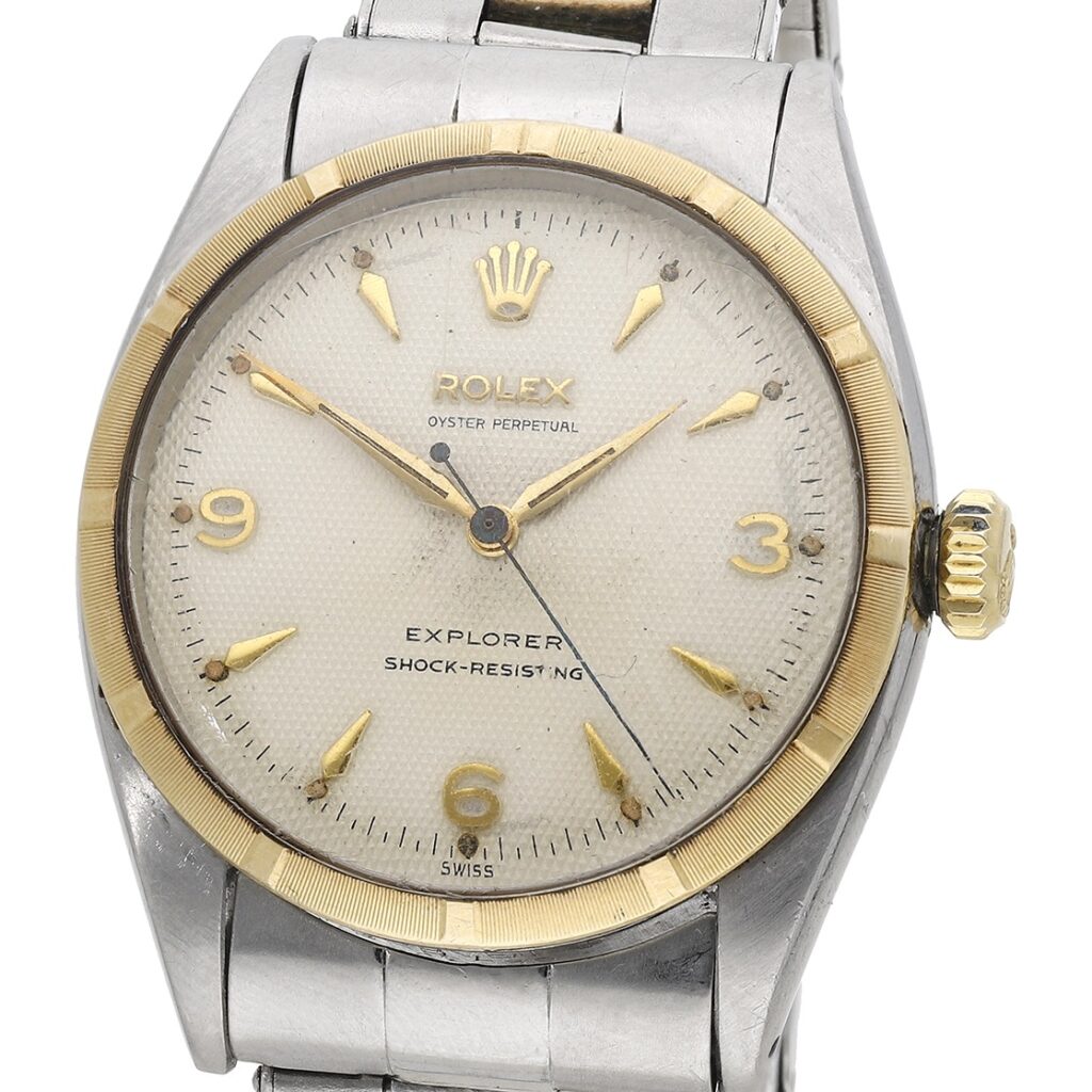 Close-up of a vintage Rolex Explorer 6299 watch with a silver and gold bezel and a metal band.