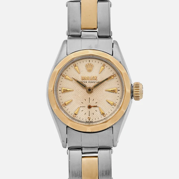 A vintage Rolex Oyster Perpetual 6507 with a gold bezel and a silver and gold metal bracelet, featuring a classic cream-colored dial.
