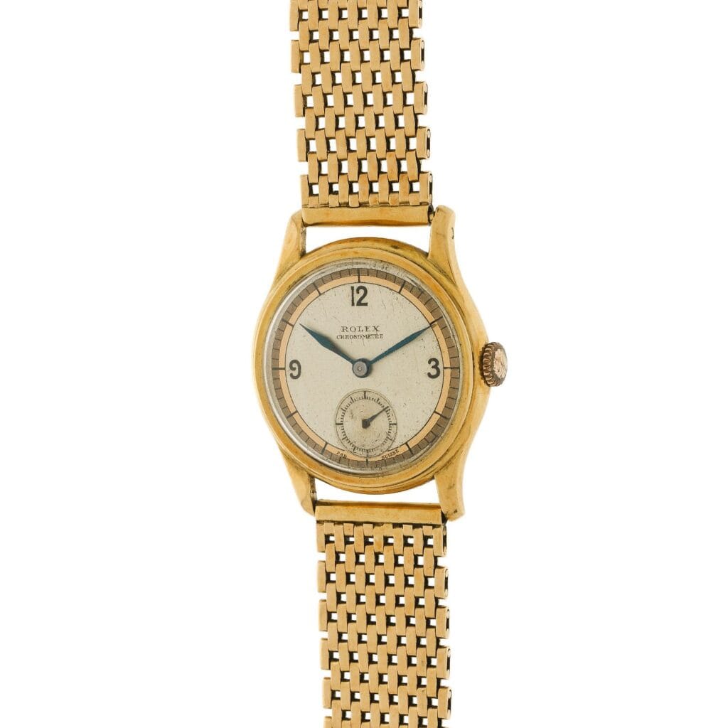 A vintage gold Rolex Oyster 3078 wristwatch with a mesh band and a small seconds subdial on a cream-colored face.