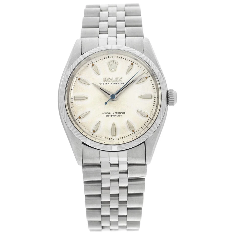A silver Rolex Oyster Perpetual 6565 wristwatch with a cream dial and metal bracelet, featuring simple hour markers.