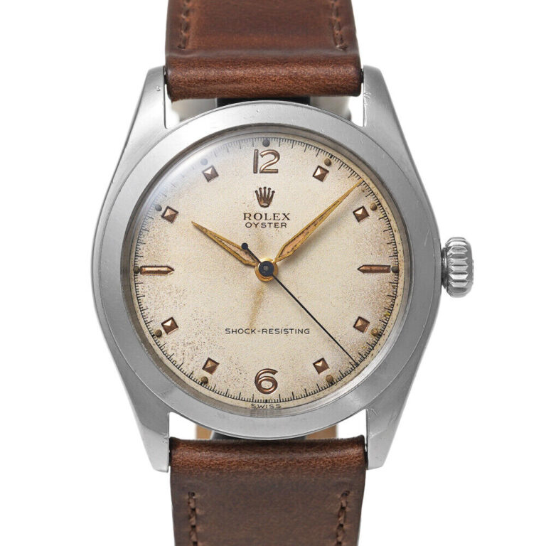 A vintage Rolex Oyster 6082 watch with a brown leather strap and cream dial, elegantly set to 10:10.