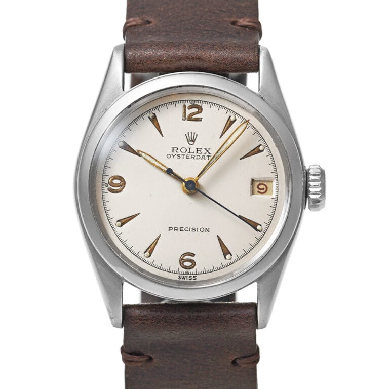 A vintage Rolex Oysterdate wristwatch with a brown leather strap and silver dial displays the time 4:41:36, showcasing the classic style of a Precision 6066.