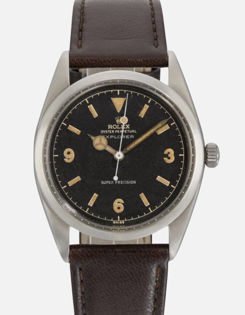 A vintage Rolex Explorer watch with a black dial, tan markers, and a brown leather strap—a timeless classic from the iconic Rolex collection.