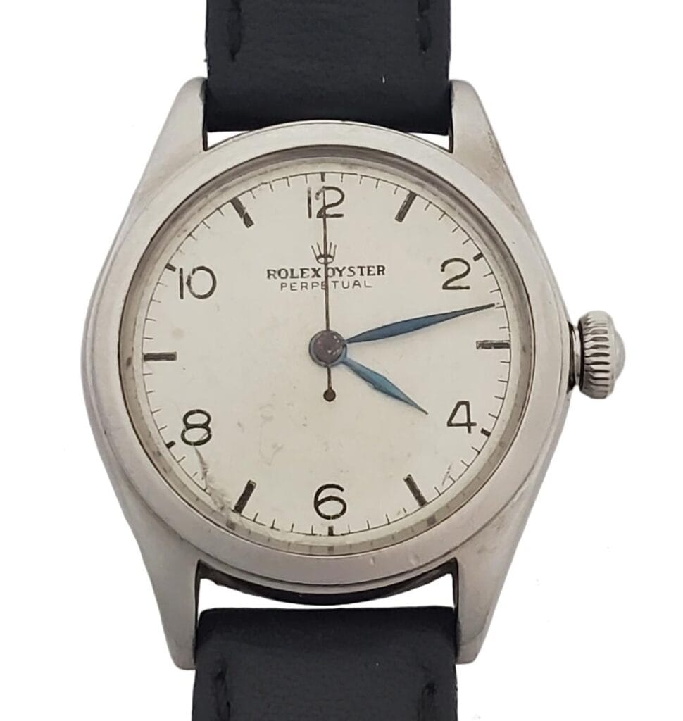 Vintage Rolex Oyster Perpetual 4846 watch featuring a white dial, black numerals, and a classic black leather strap.