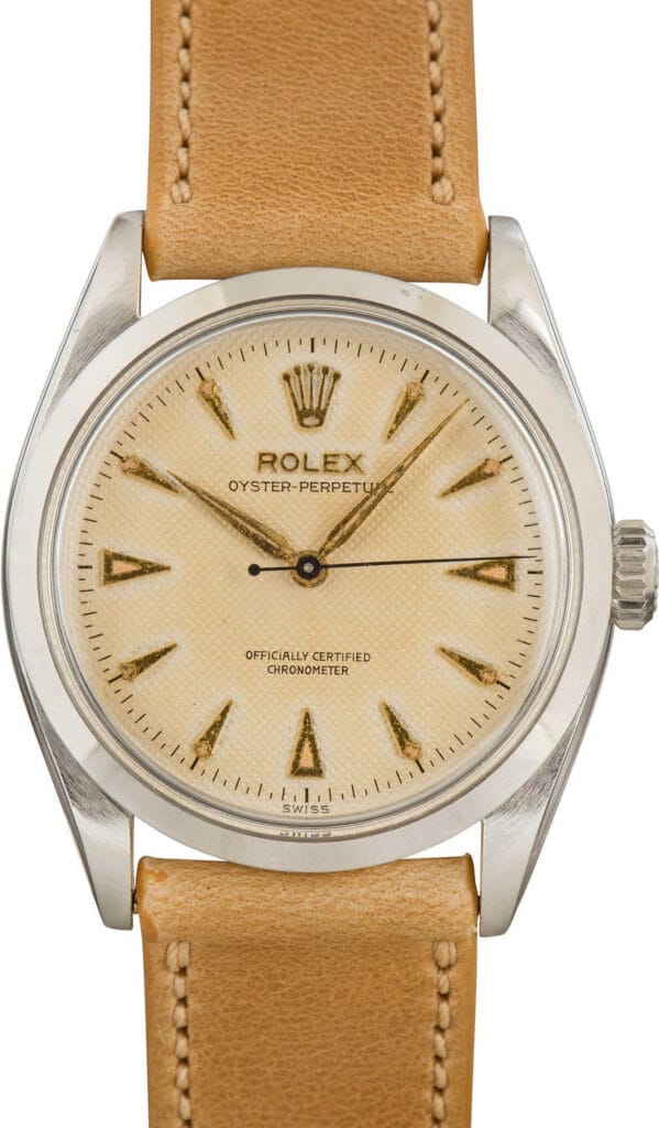 A vintage Rolex Oyster Perpetual 3708 watch featuring a beige dial and tan leather strap.