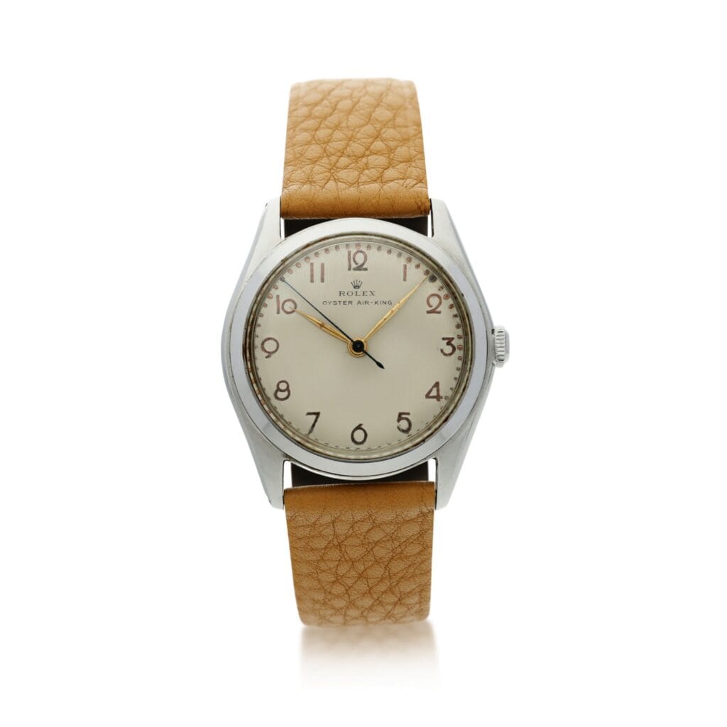A vintage Rolex Air-King 4925 watch with a tan leather strap and a silver case, featuring Arabic numerals on a white dial.