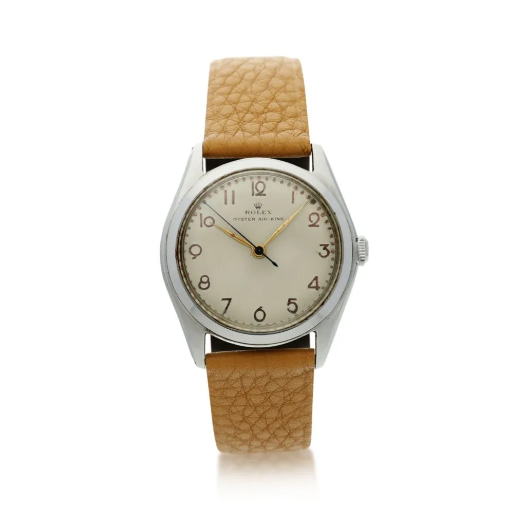 A vintage Rolex Air-King 4925 watch with a tan leather strap and a silver case, featuring Arabic numerals on a white dial.