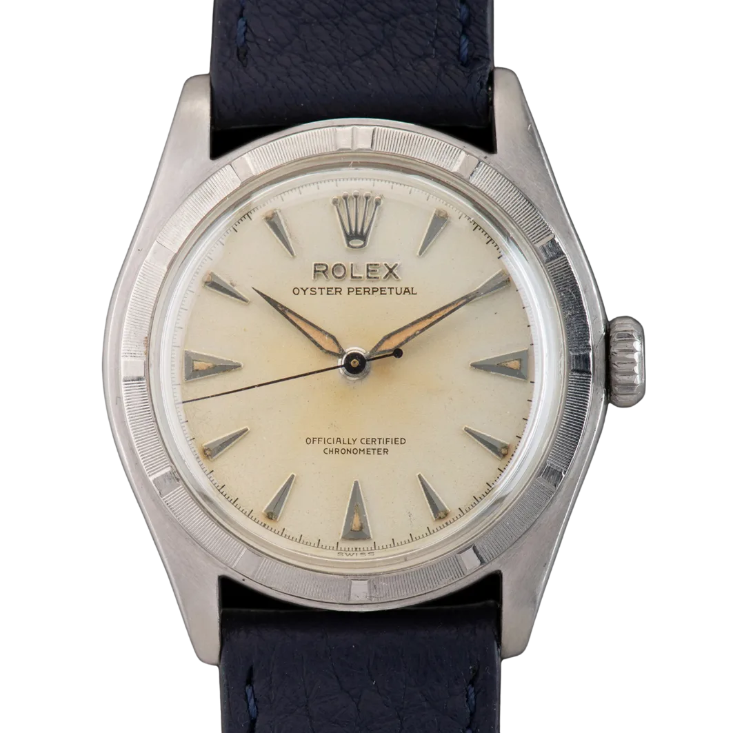 A vintage Rolex Oyster Perpetual 6107 watch featuring a cream dial and black leather strap.