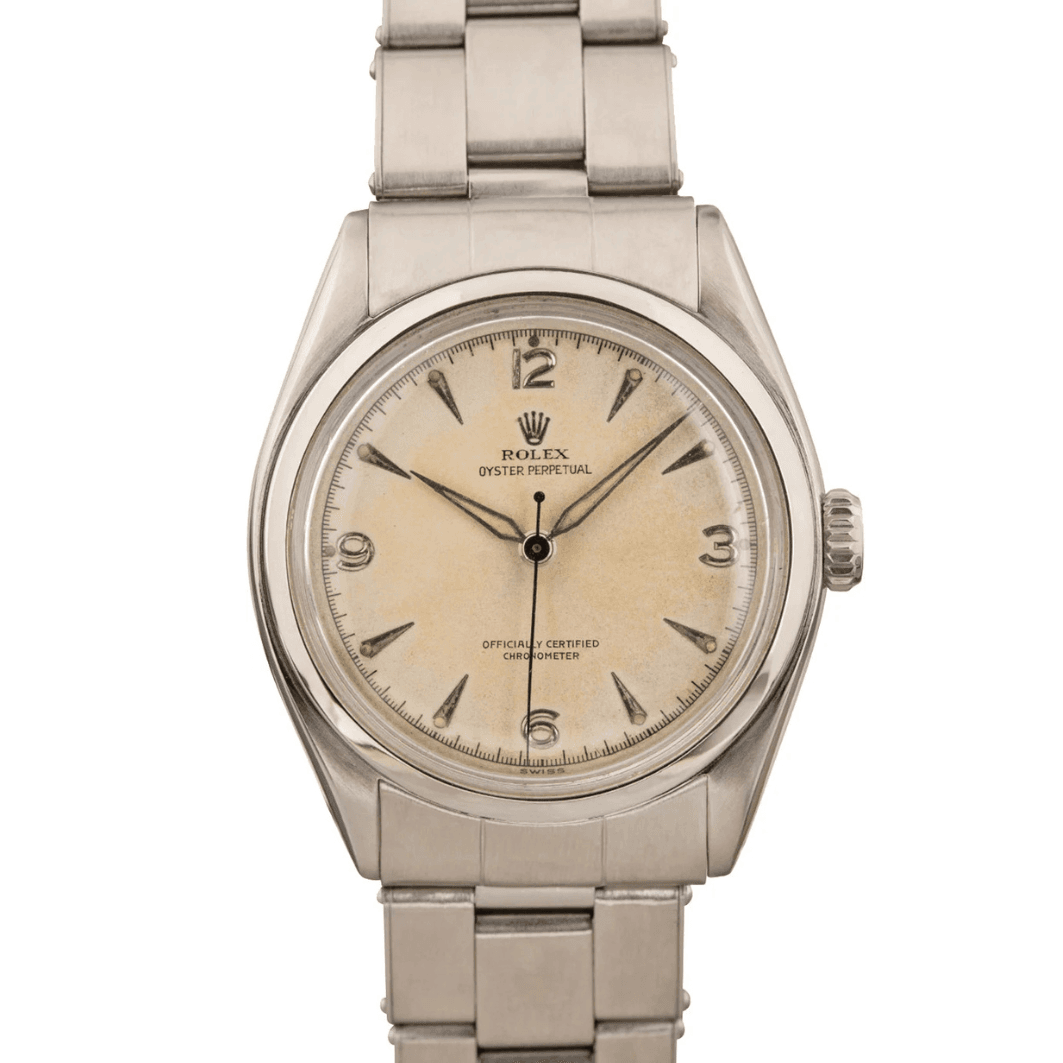 A vintage Rolex Oyster Perpetual 6084 silver watch with a cream dial and metal bracelet.