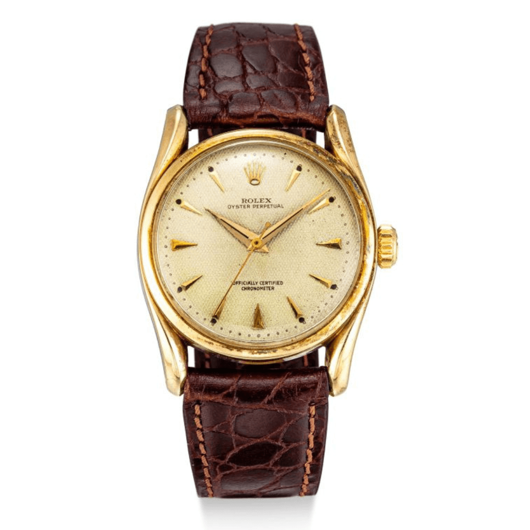 Vintage gold Rolex Oyster Perpetual 6102 watch with a textured brown leather strap and a light gold dial.