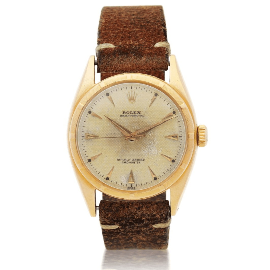 Vintage Rolex Oyster Perpetual wristwatch with a gold case, aged dial, and a worn brown leather strap.