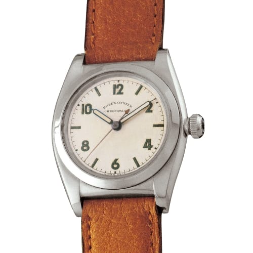 A vintage Rolex Oyster Perpetual wristwatch with a brown leather strap and a white dial featuring green numerals.