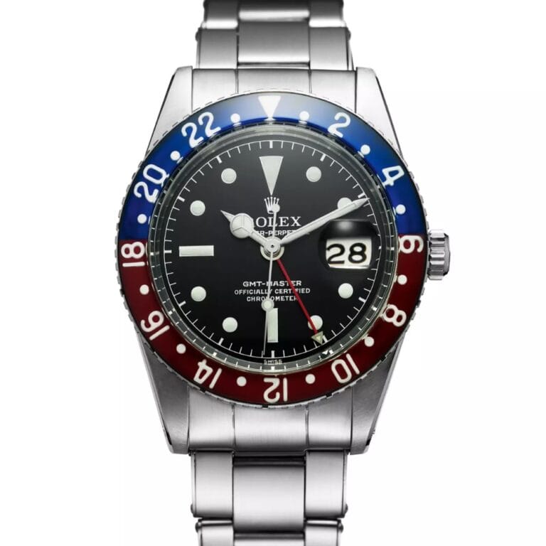 A stainless steel Rolex GMT-Master wristwatch with a red and blue bezel, black dial, and metal bracelet, inspired by the iconic 6542 model.