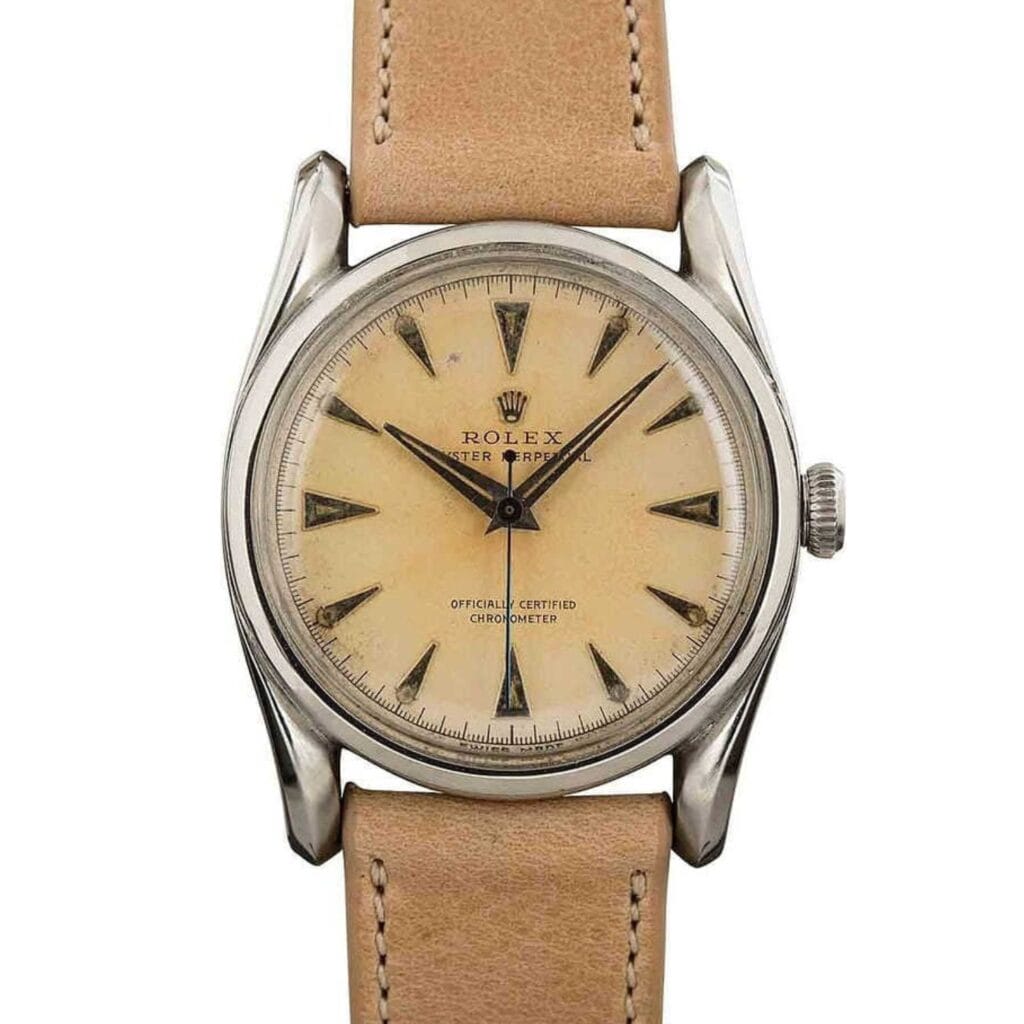 Vintage Rolex Oyster Perpetual 1508 wristwatch featuring a tan leather strap and cream dial with elegant silver hour markers and hands.