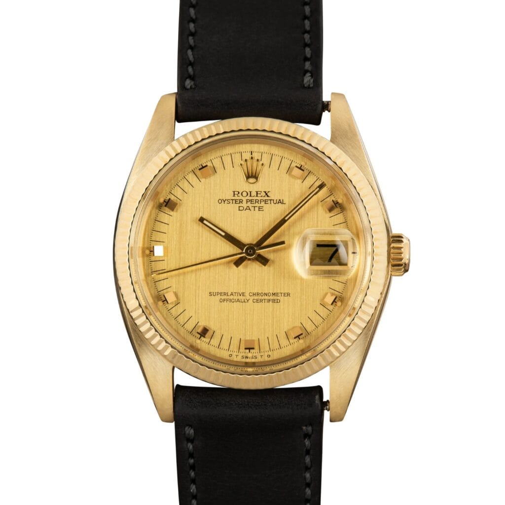 A gold Rolex Oyster Perpetual Date 1503 wristwatch with a black leather strap and date display, shown against a white background.