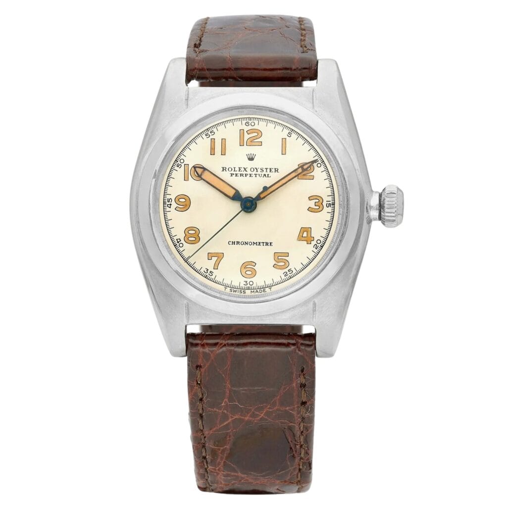 Vintage Rolex Oyster Perpetual Date 1102 watch featuring a cream dial, brown leather strap, and classic Arabic numerals.