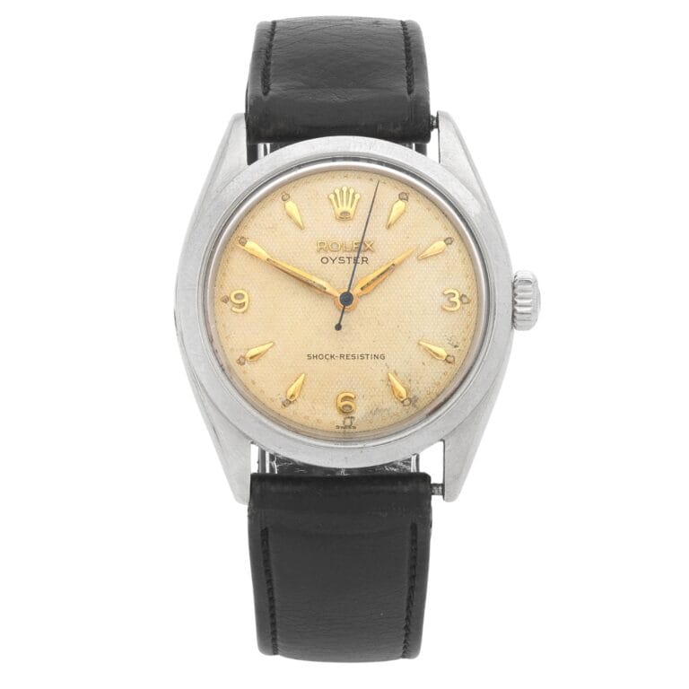Vintage Rolex Oyster 6480 watch with a cream dial, gold hour markers, and a black leather strap.
