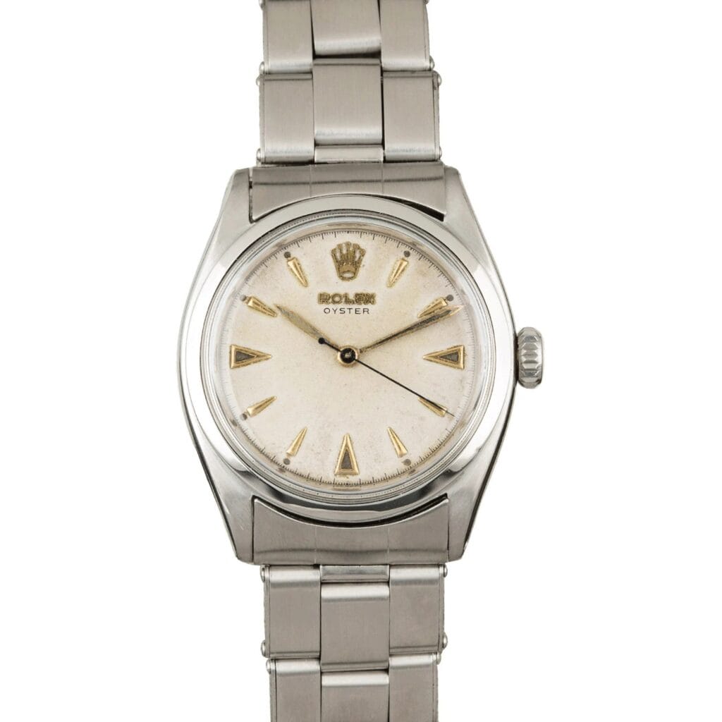 A vintage Rolex Oyster 6022 wristwatch with a silver metal band and a white dial featuring gold hour markers.