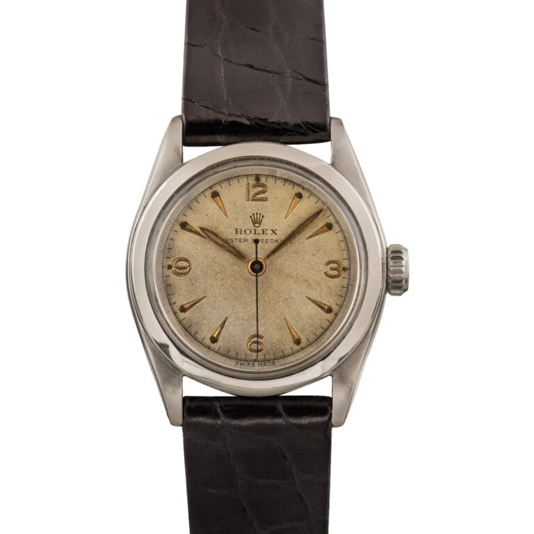 Vintage Rolex Oyster Speedking 6020 wristwatch with a cream-colored dial, gold hour markers, and a black leather strap.