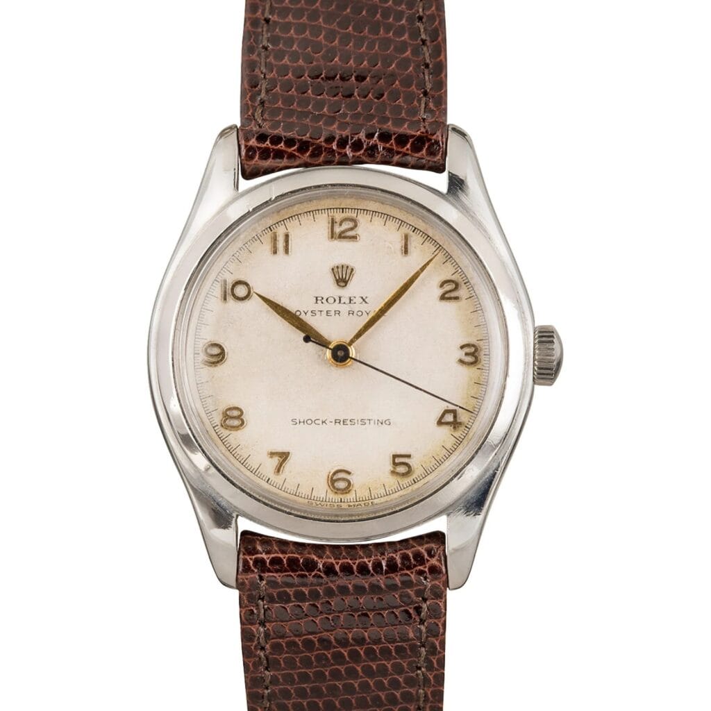 Vintage Rolex Oyster Royal 6144 watch with a brown leather strap and cream dial displaying gold Arabic numerals.