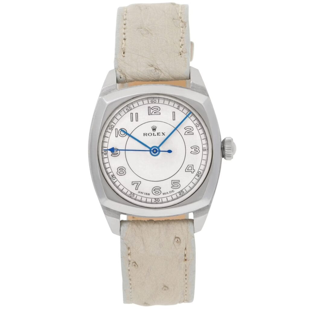 A Rolex Oyster wristwatch featuring a silver case, white dial, blue hands, and a light beige leather strap.