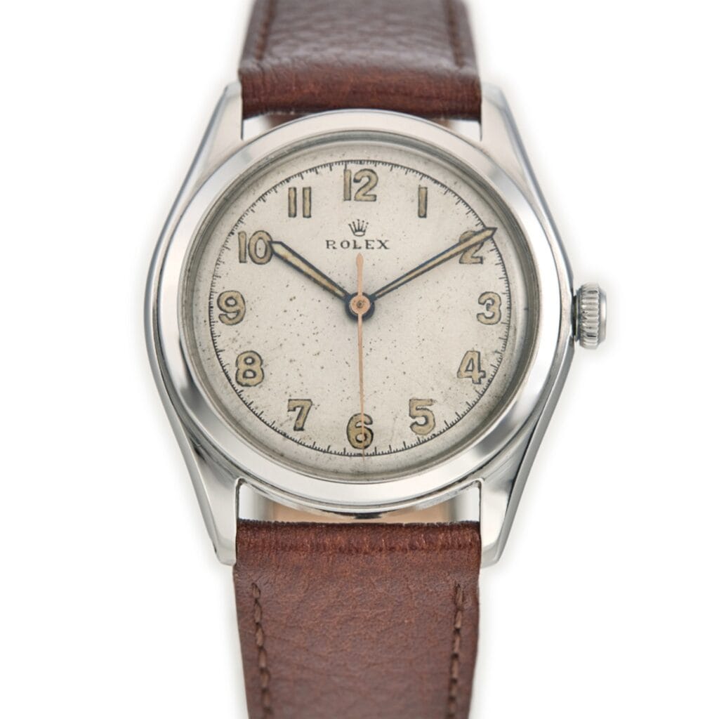 A vintage Rolex Oyster 4499 wristwatch with a brown leather strap and a silver dial displaying Arabic numerals.