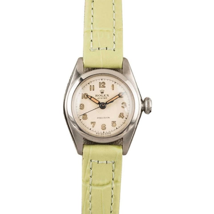 A vintage Rolex watch with a pale green leather strap and a round silver dial displaying Arabic numerals, this classic piece echoes the timeless elegance of the Oyster 4271.