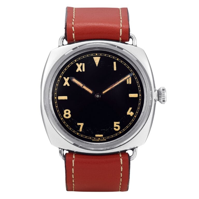 Wristwatch with a black dial, tan numbers, and a brown leather strap with white stitching.