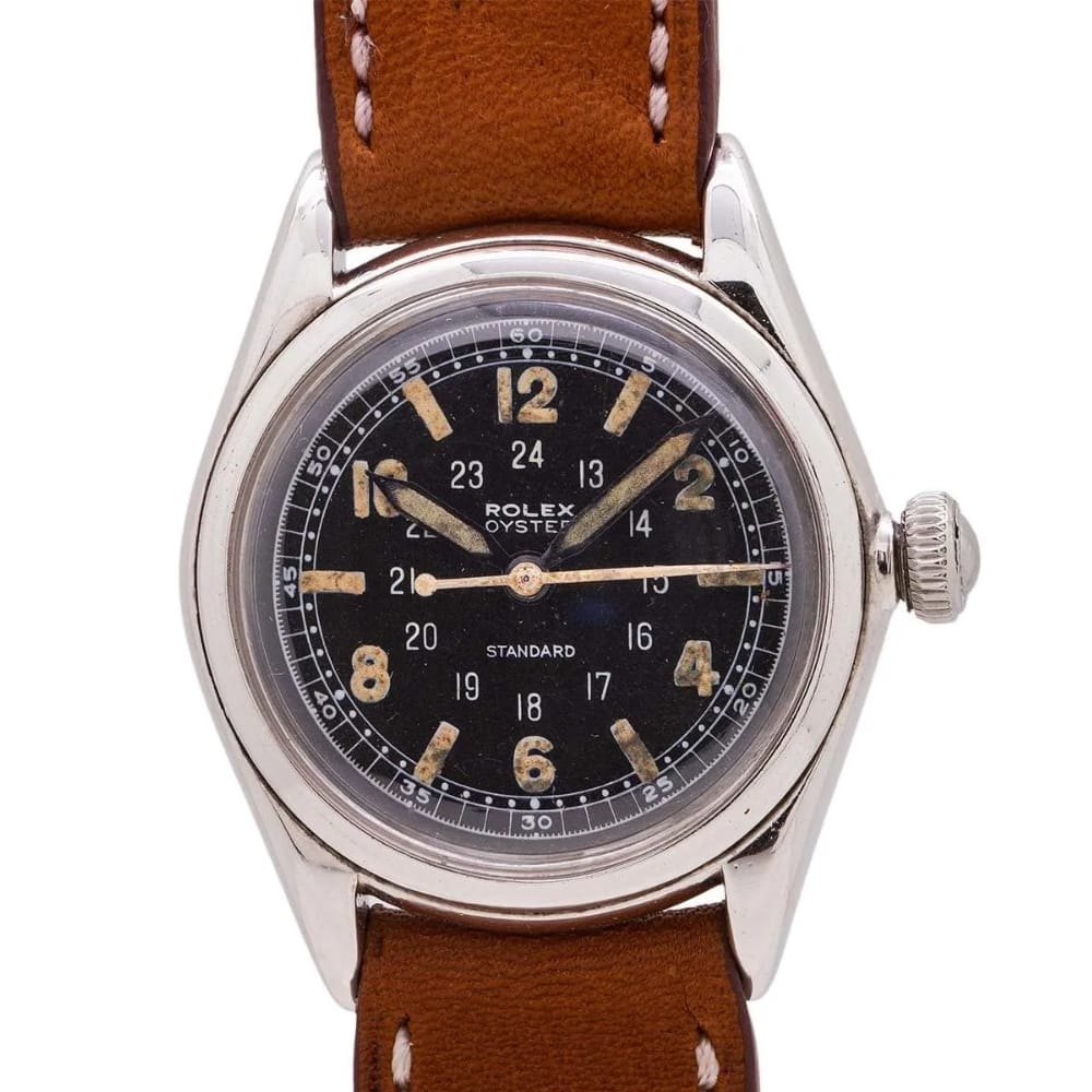 A vintage Rolex Oyster 3351 watch with a brown leather strap and a black dial displaying both 12 and 24-hour markers.