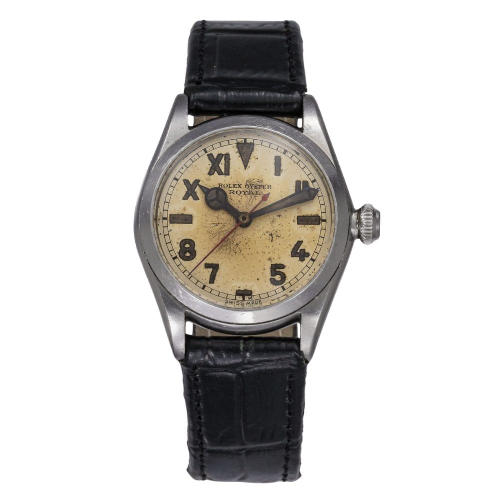 A vintage Rolex Oyster wristwatch featuring a worn beige dial, black leather strap, and large numeral markers.