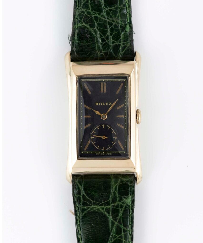 Rectangular gold vintage Rolex Prince watch with a black face and green textured leather strap, viewed from above.